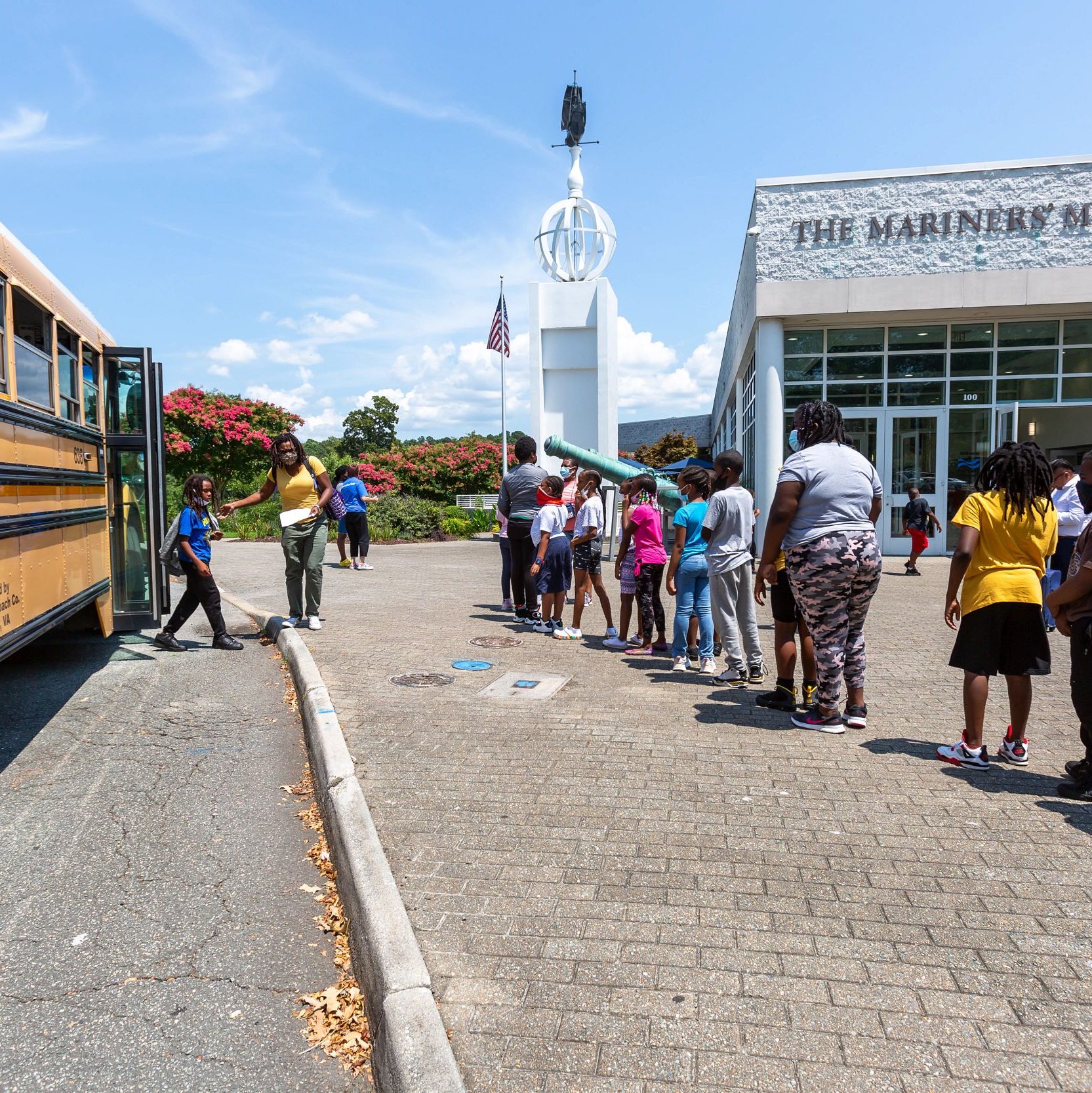 Children waiting in line for school bus in front of Museum