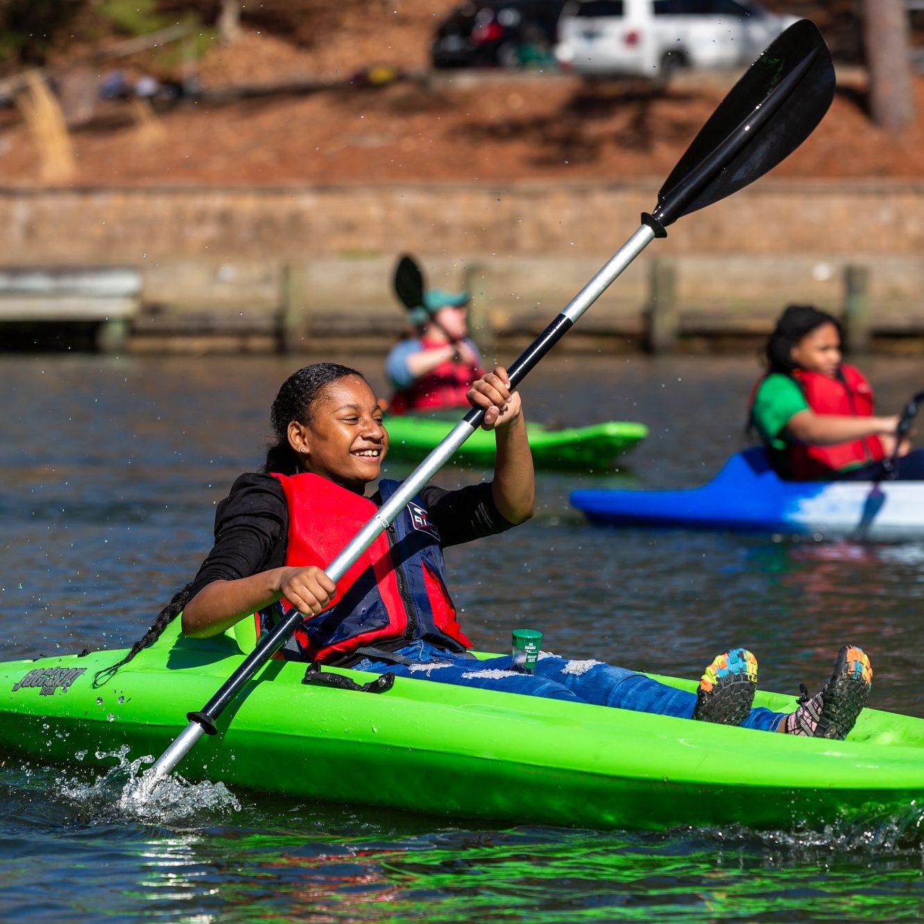 child smiles while kayaking on Mariners' Lake.