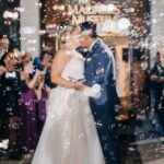 Bride and groom kissing while surrounded by bubbles.