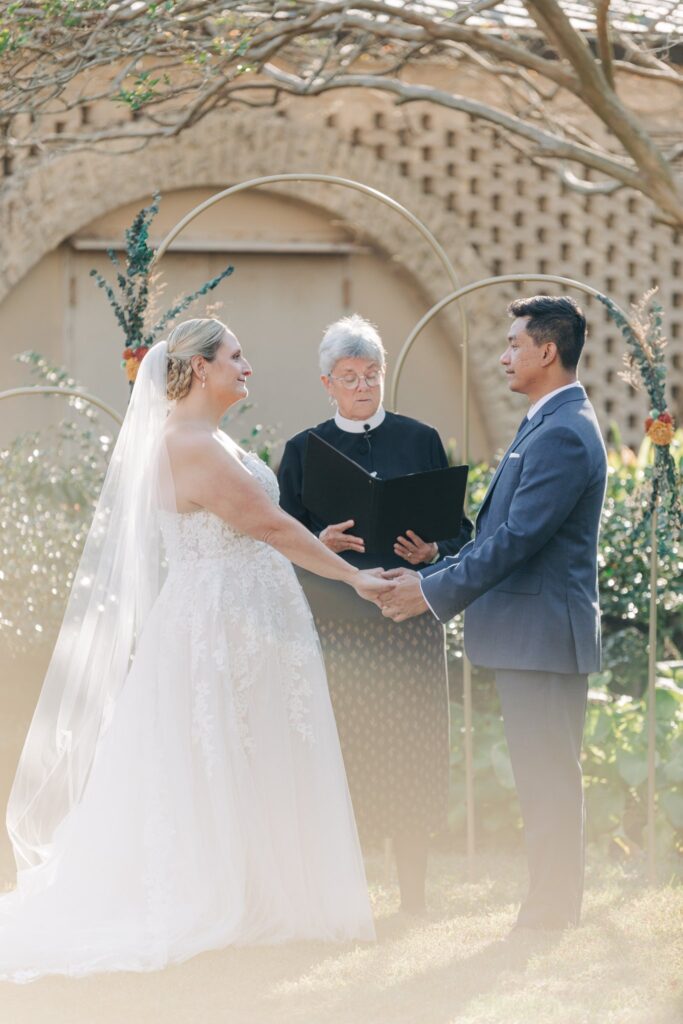 Bride, groom, and officiant at wedding altar.