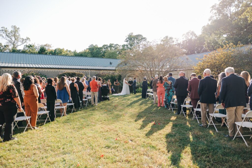 Panoramic view of the guests standing while the bride and groom are at the altar.