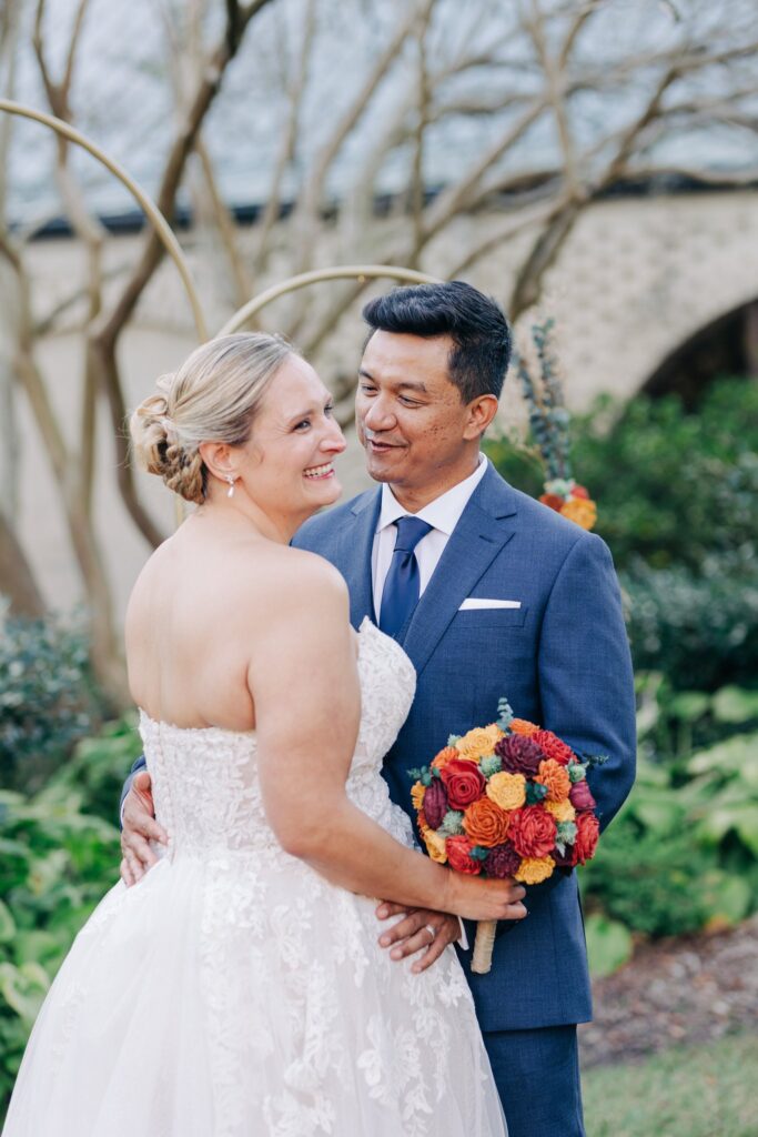 Groom looking at bride while they are both smiling.