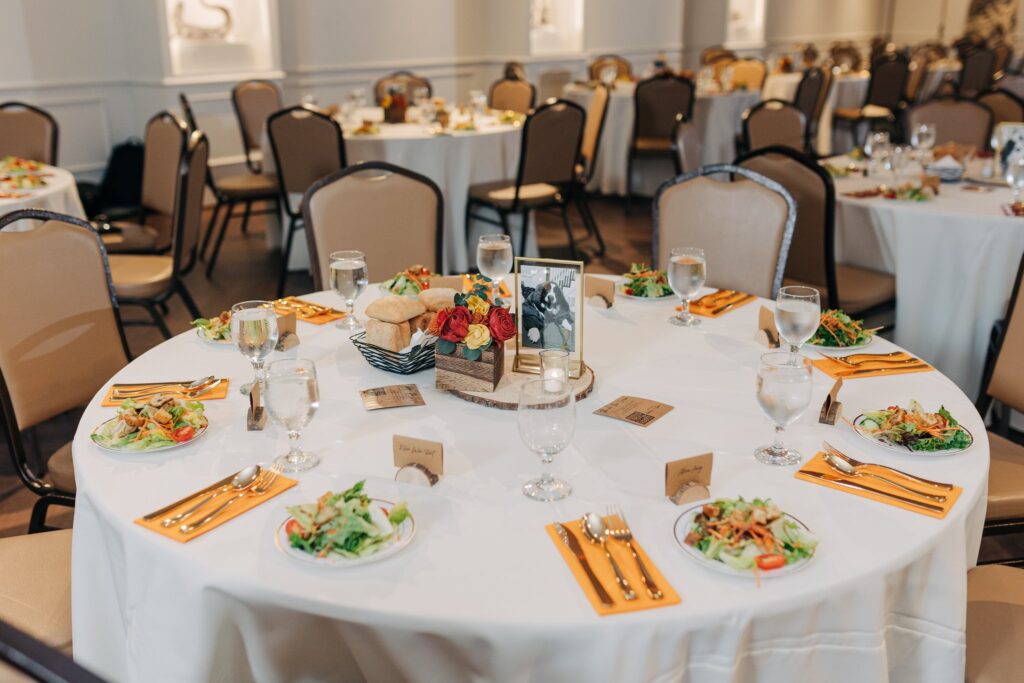Wedding guest tables set with silverware, glasses, and salads.